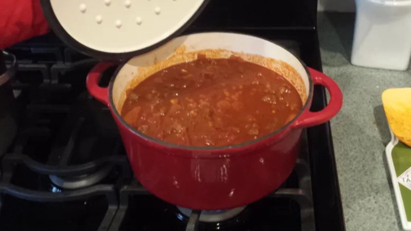 Traditional Texas Chili simmering on the stove in a red Dutch oven — rich, hearty, and full of smoky flavor.