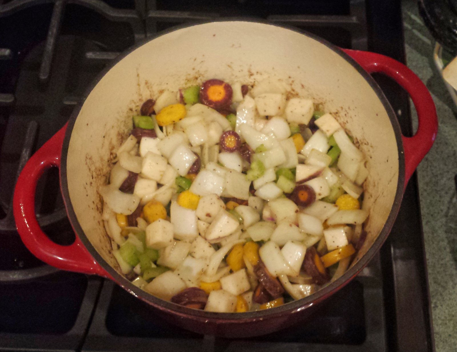Carrots, onion, celery carrots, onion, diced turnip and diced celery stalks cooking in the dutch oven.