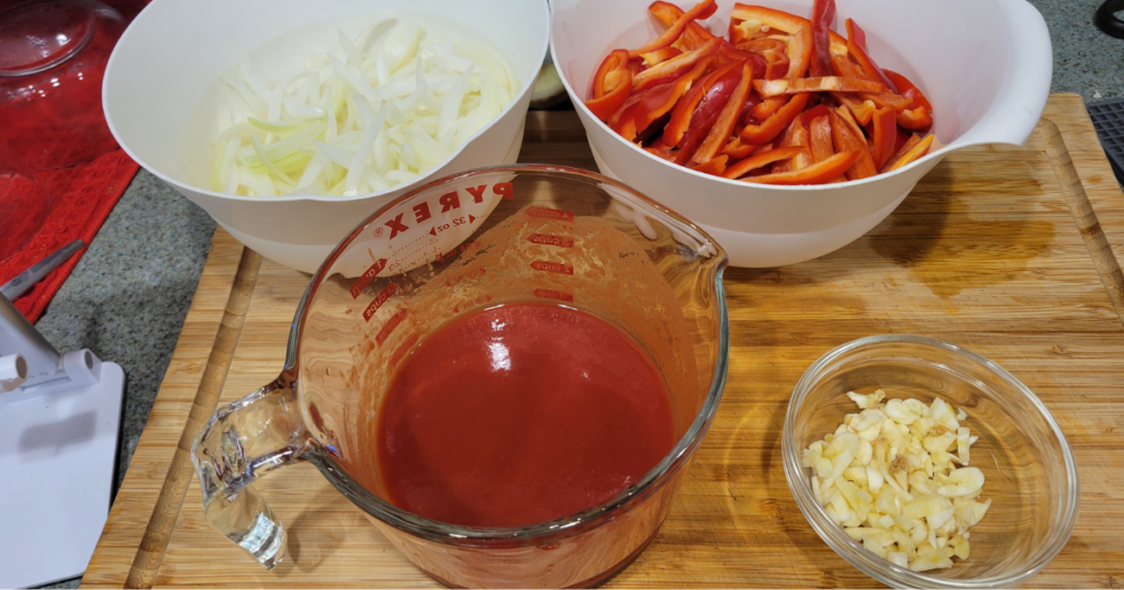 This is a picture of the following ingredients: Italian Sweet Peppers, sliced onions, chopped garlic, and tomato paste.
