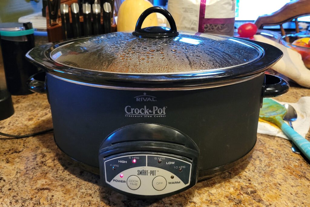 Slow cooker filled with London Broil chili simmering on the counter — steam rising under the lid during a cozy weekend cook in Breckenridge.