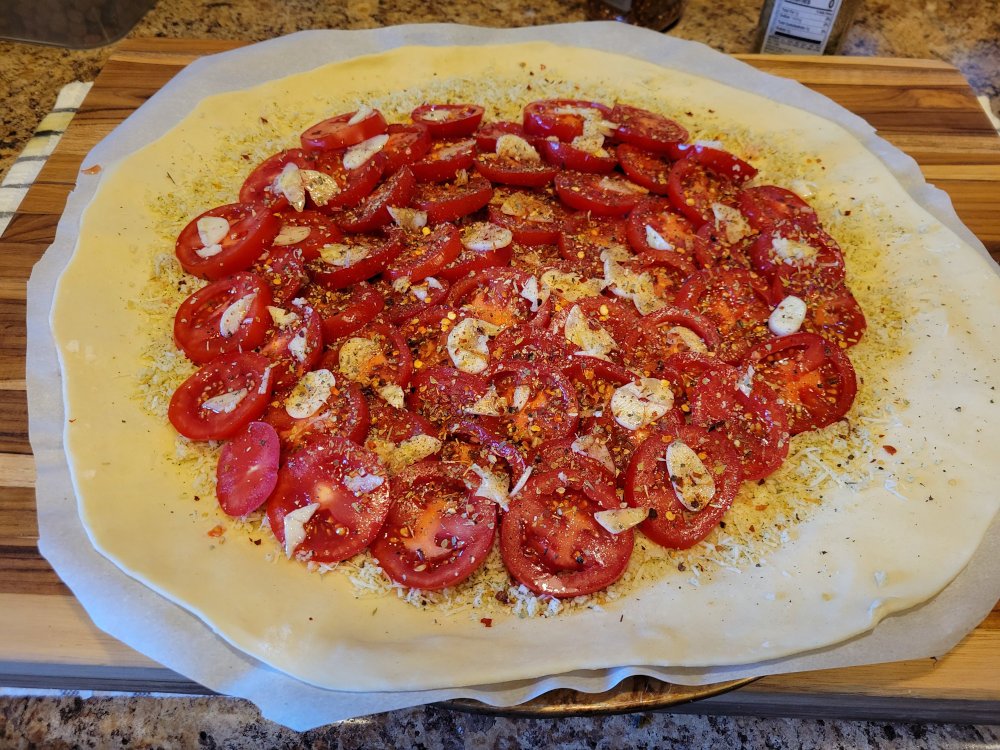 Rolled out galette dough topped with tomatoes and garlic.