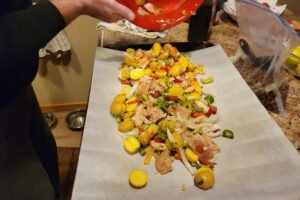 pouring the chicken, potatoes, and vegetables onto the sheet pan