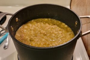 Chicken pozole verde simmering in a large pot with hominy and green chile sauce.