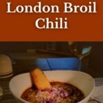 Pinterest graphic for Slow Cooker London Broil Chili, showing a cozy bowl of chili with cheese, onions, and cornbread, styled with warm orange and olive tones.