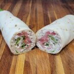 Close-up of a sliced turkey salad wrap showing creamy jalapeño turkey salad with tomatoes and lettuce.