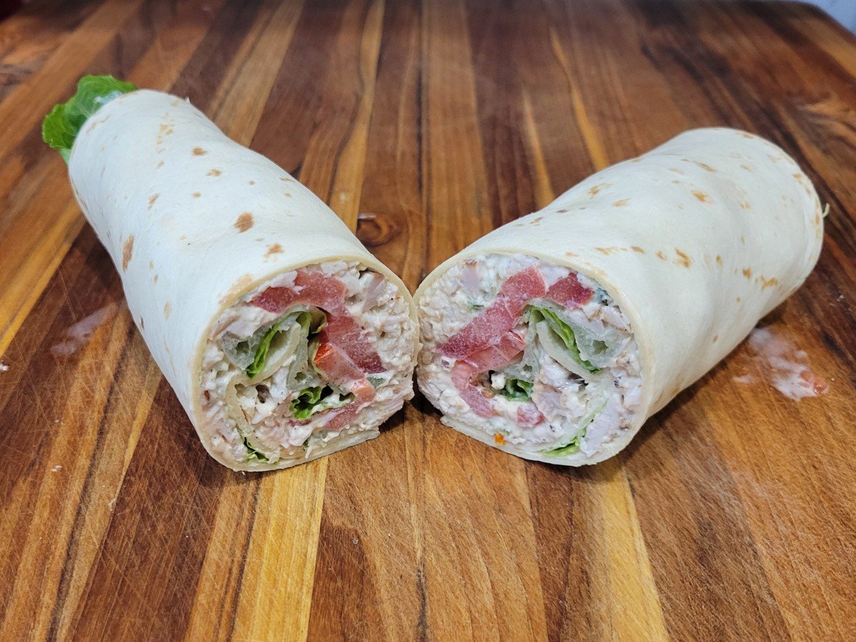 Close-up of a sliced turkey salad wrap showing creamy jalapeño turkey salad with tomatoes and lettuce.