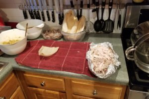 A single corn husk placed on a red kitchen towel, ready for masa and filling.