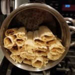 Tamales arranged upright in a large steamer pot before cooking.