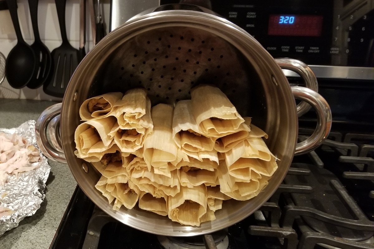 Tamales arranged upright in a large steamer pot before cooking.