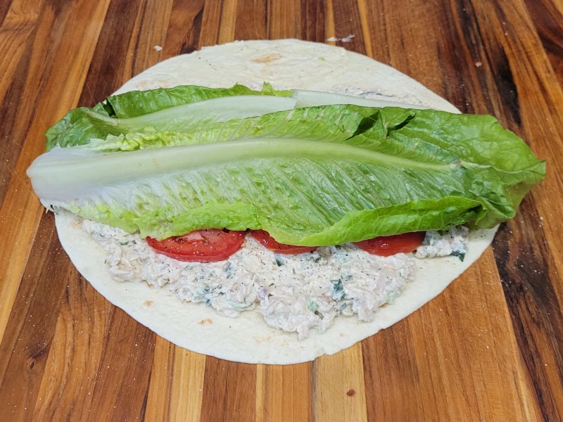 Turkey Salad Wrap – Step 3 Add Romaine Turkey salad wrap being assembled with whole romaine lettuce leaves layered over the tomatoes.